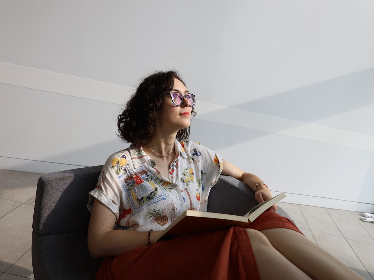 A woman sitting quietly by a window, reading, in soft daylight